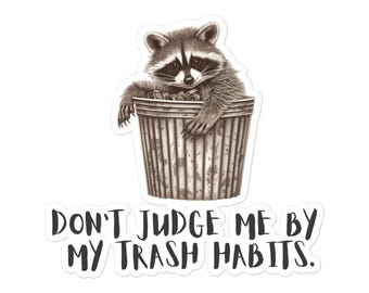 Puede incluir: Una pegatina con un mapache sentado en un cubo de basura. El mapache es gris y blanco con una máscara negra. El cubo de basura es marrón y tiene líneas verticales. El texto "DON'T JUDGE ME BY MY TRASH HABITS." está debajo.