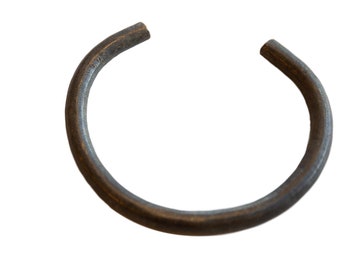 May include: A simple, circular, metal ring. The ring is made of a dark, metallic material and has a smooth, slightly textured surface.