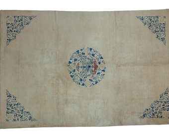 May include: A cream-colored rug with a blue and red circular design in the center. The rug has blue and white corner designs.