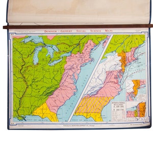 以下が含まれることがあります： 緑、ピンク、黄色、青色で描かれた北米のヴィンテージ地図。地図には「DENOYER-GEPPERT SOCIAL SCIENCE MAPS」と書かれており、青い縁取りのある木製のバーに取り付けられています。
