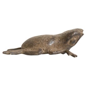 May include: A bronze frog figurine with a textured surface. The frog is lying on its belly with its legs outstretched.