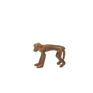 Peut inclure: Une petite figurine de singe en bronze avec une surface texturée détaillée. Le singe est debout sur ses quatre pattes, la tête légèrement inclinée sur le côté.