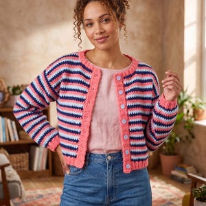 May include: A long-sleeved crochet cardigan featuring horizontal stripes in coral, navy blue, and light blue. The garment has a round neckline, a solid coral button placket, and light blue circular buttons down the front center.