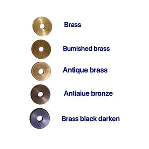 May include: A selection of brass washers in various finishes, including brass, burnished brass, antique brass, antique bronze, and brass black darken. Each washer has a central hole and is displayed against a white background. The text labels each finish.