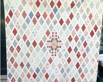 May include: A large quilt with a diamond pattern in shades of red, blue, and white. The quilt is made of various floral fabrics and has a central diamond with a checkered pattern.