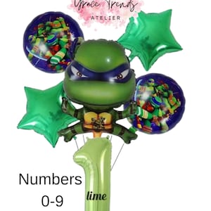 Könnte beinhalten: Eine Sammlung von Luftballons zum Thema Teenage Mutant Ninja Turtles. Das Herzstück ist ein grüner Schildkröten-Luftballon mit blauer Maske. Enthält zwei runde Ballons mit den Schildkröten, zwei grüne sternförmige Ballons und einen limettengrünen Ballon mit der Zahl eins, 102 cm hoch.