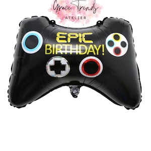 Op de afbeelding: Zwarte folieballon in de vorm van een gamecontroller met de tekst "EPIC BIRTHDAY!" in het geel. De controller heeft kleurrijke knopdetails en is ontworpen voor een verjaardagsfeest. De ballon is van Grace Trends Atelier.