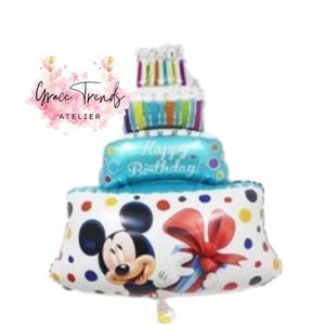 May include: A three-tiered birthday cake balloon featuring Mickey Mouse, a red bow, and colorful polka dots. The middle tier reads "Happy Birthday!" in blue. The top tier has candles. The balloon is white, blue, and multi-colored.