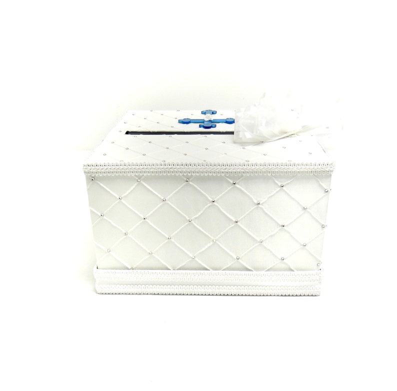 May include: White satin wedding card box with a blue cross design and a diamond pattern. The box has a slot on the top for cards.