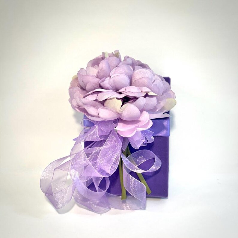 May include: A small purple gift box with a lavender flower bouquet tied with a sheer purple ribbon.