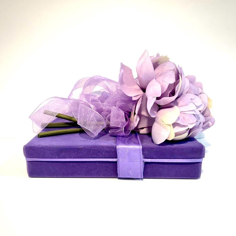 May include: A purple velvet gift box with a lavender flower bouquet tied with a sheer purple ribbon.