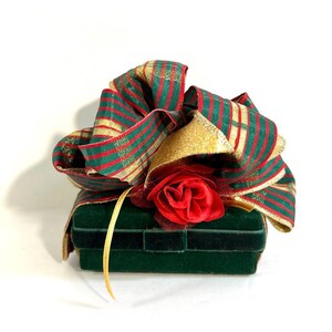 May include: A green velvet box with a red and green striped ribbon and a red rose on top.
