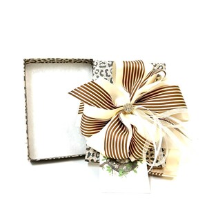 May include: A gift box with a leopard print design and a large brown and white striped bow. The bow has a small rhinestone embellishment in the center.