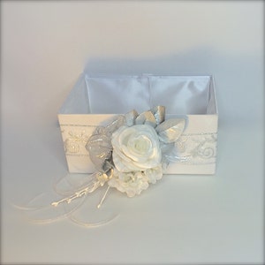 May include: White satin box with a silver and white floral embellishment. The box is open and empty.