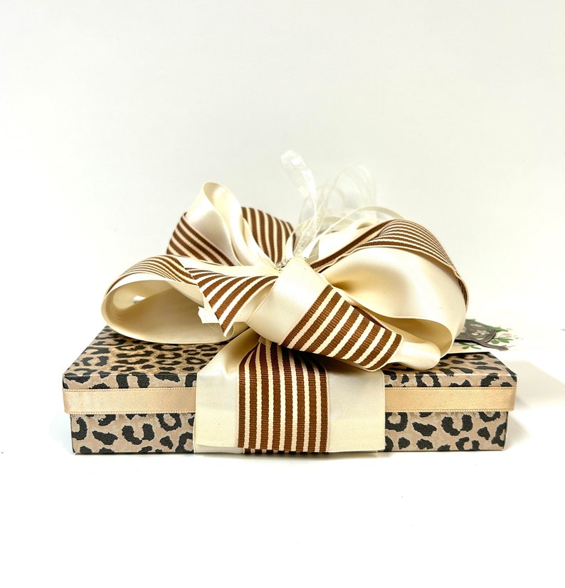 May include: A gift box with a leopard print design and a large brown and white striped bow.