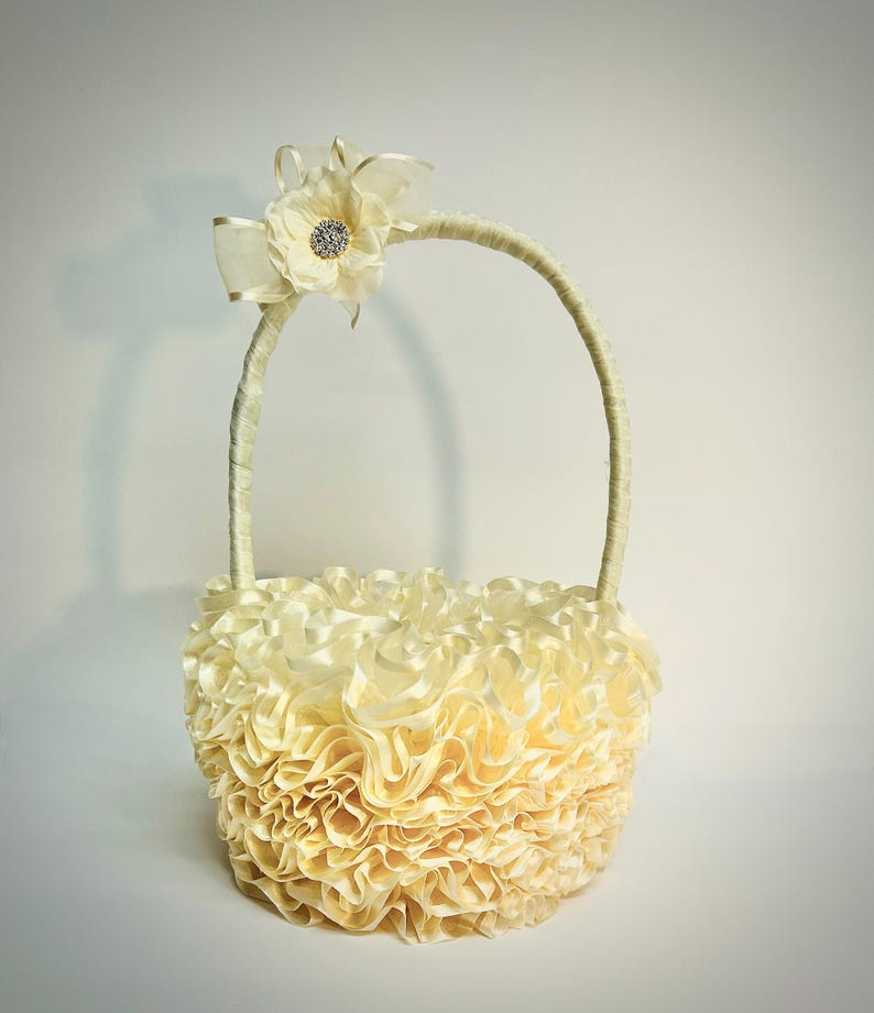 Peut inclure: Un panier cr&egrave;me avec un design &agrave; volants et une poign&eacute;e incurv&eacute;e. Le panier est orn&eacute; d'une fleur cr&egrave;me et d'une d&eacute;coration scintillante. La poign&eacute;e est envelopp&eacute;e d'un mat&eacute;riau cr&egrave;me assorti. Ce panier d&eacute;coratif convient aux mariages ou &eacute;v&eacute;nements sp&eacute;ciaux.