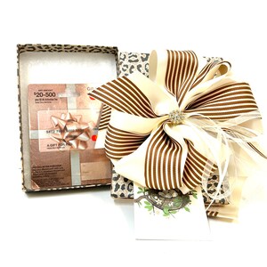 May include: A gift box with a leopard print design, a large brown and white striped bow, and a gift card with the text "ANY AMOUNT $20-500 plus $2.50 Activation Fee" and "A GIFT FOR YOU".