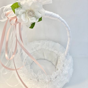 May include: White flower girl basket with a pink satin ribbon and a white flower with a rhinestone center.