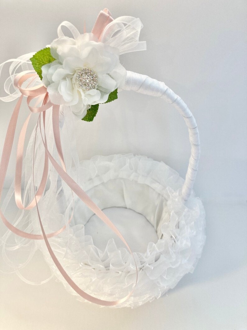May include: White flower girl basket with a pink satin ribbon and a white flower with a rhinestone center.