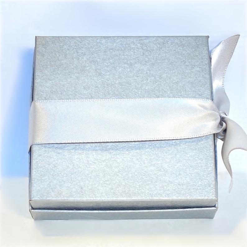 May include: A silver gift box with a white satin ribbon tied around it.