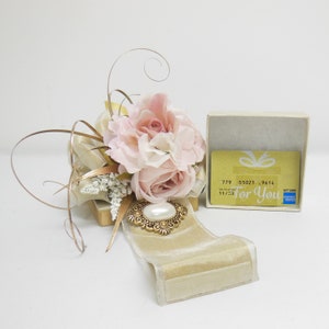 K&ouml;nnte beinhalten: Eine Geschenkbox mit einem rosafarbenen Blumenarrangement und einem goldenen Band. Die Box enth&auml;lt eine Geschenkkarte mit dem Text "F&uuml;r Dich" und einer Geschenkkarten-Nummer.