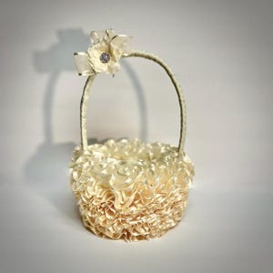 Peut inclure: Panier de demoiselle d'honneur ivoire avec un design &agrave; volants. Le panier est dot&eacute; d'une poign&eacute;e incurv&eacute;e et est orn&eacute; d'un n&oelig;ud et d'une fleur avec un centre en strass. Le panier est fait d'un tissu doux et textur&eacute;.