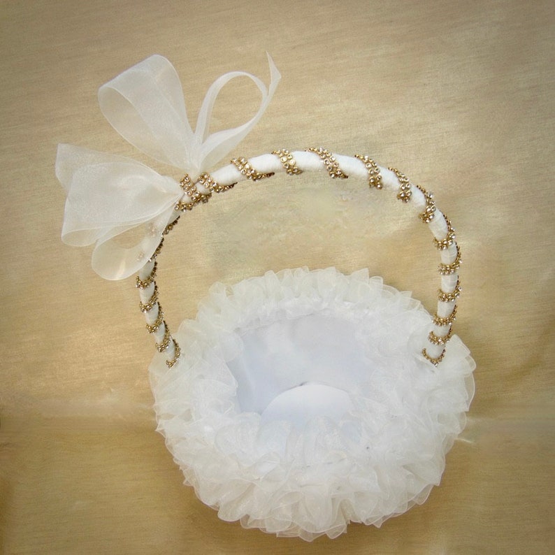 K&ouml;nnte beinhalten: Wei&szlig;er Blumenm&auml;dchenkorb mit einem gold-wei&szlig;en Perlenhenkel und einer wei&szlig;en Schleife aus Satin.