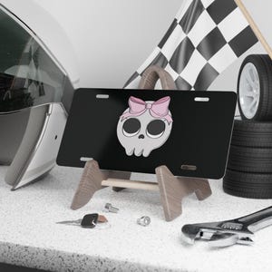 Targa con teschio femminile e fiocco rosa: decorazione audace per auto