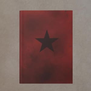 Könnte beinhalten: Ein rotes Buch mit einem schwarzen Stern in der Mitte. Der Einband hat ein verwittertes, strukturiertes Aussehen. Das Buch ist rechteckig und scheint geschlossen zu sein.