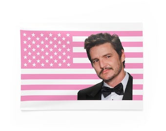 Puede incluir: Una impresión rectangular con un diseño de bandera estadounidense rosa y blanca y un retrato de un hombre con esmoquin negro y pajarita. El hombre tiene cabello oscuro y bigote, y está mirando al espectador.