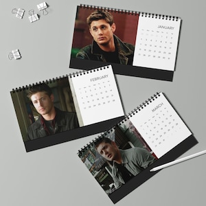 May include: Desk calendars featuring images of a person, with the months of January, February, and March visible. Each calendar has a black base and a spiral binding. The calendar pages display the days of the month in a simple, clean font.