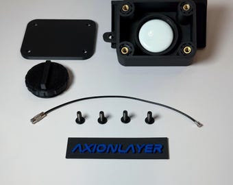 May include: An assortment of black 3D-printed components, including a rectangular box with a white circular element, a lid, a circular cap, screws, a wire, and a rectangular label with the text "AXIONLAYER" in blue.