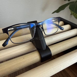 May include: A pair of blue Piranha Optics glasses with rectangular frames resting on a black nose-shaped stand. The glasses feature clear lenses with a blue light reflective coating and the text Piranha Optics printed on the inner temple arm.