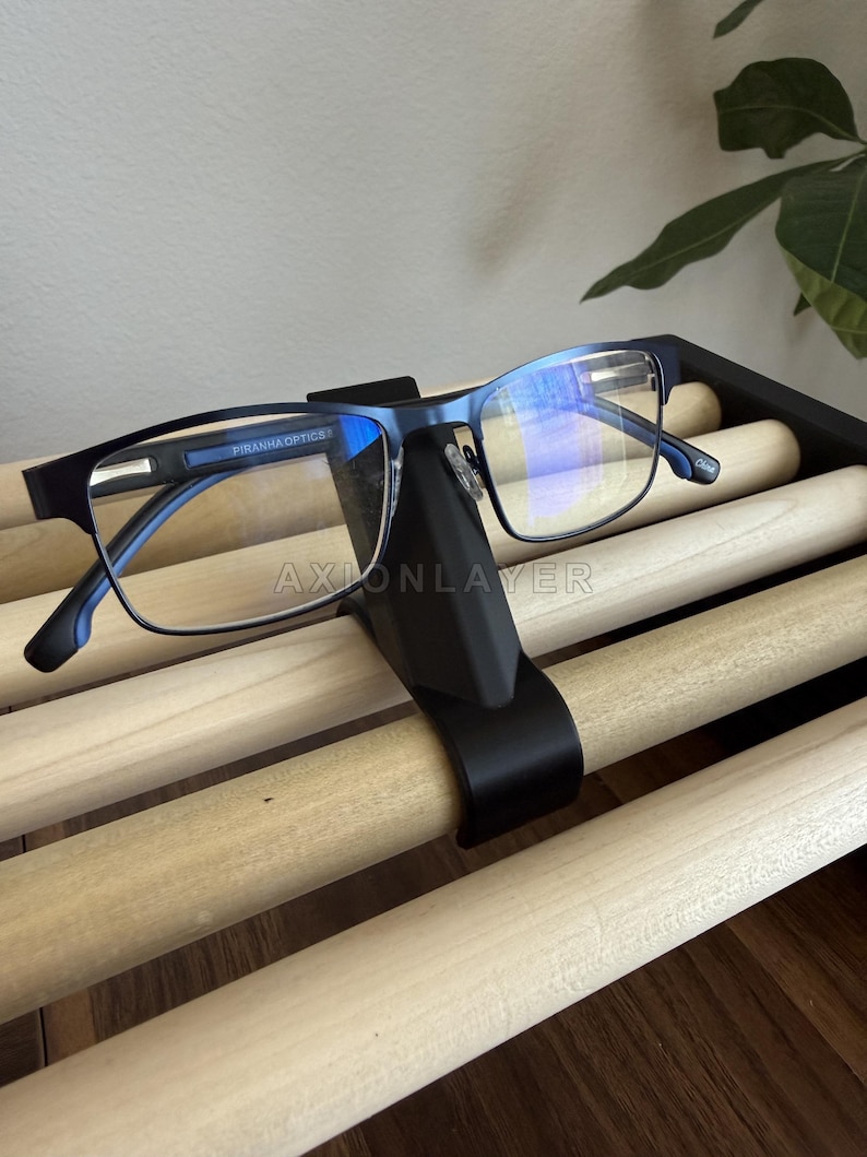 May include: A pair of blue Piranha Optics glasses with rectangular frames resting on a black nose-shaped stand. The glasses feature clear lenses with a blue light reflective coating and the text Piranha Optics printed on the inner temple arm.