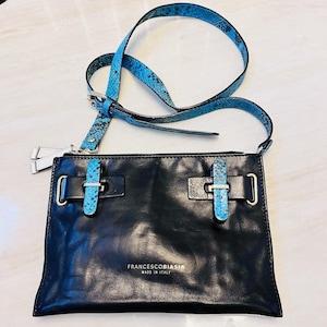 Puede incluir: Bolso bandolera de cuero negro con correa y detalles en azul con estampado de piel de serpiente. El bolso presenta dos hebillas decorativas con detalles azules y el texto "FRANCESCOBIASIA MADE IN ITALY".