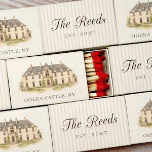 May include: A collection of rectangular matchboxes featuring a watercolor illustration of Oheka Castle, NY, and the text The Reeds EST. 2027. The boxes have a cream and light gray striped pattern. One open box reveals wooden matches with red tips.