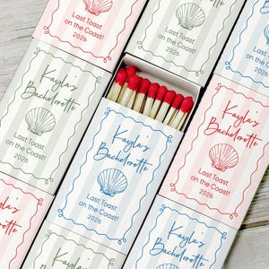 May include: A collection of matchboxes with red-tipped matches. Each box features a seashell graphic and the text "Kayla's Bachelorette" and "Last Toast on the Coast! 2026" in various colors, including pink, blue, and green.