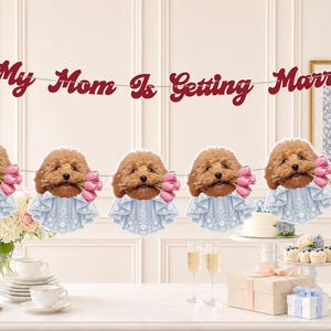 May include: A decorative banner featuring the text My Mom Is Getting Married in dark red script, interspersed with cutouts of brown poodles wearing light blue lace collars and holding pink tulips in their mouths, strung on a thin white cord.
