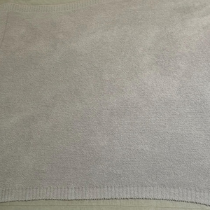 Pu&ograve; includere: Una coperta lavorata a maglia color grigio lavanda chiaro con una consistenza morbida e soffice. La coperta presenta un ampio bordo a coste lungo i lati e un motivo a maglia denso e uniforme su tutto il corpo principale, creando un colore.