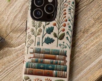 May include: A phone case featuring a stack of books and botanical illustrations in teal, orange, and green. The case has a beige background and is decorated with various floral and plant designs. The phone case is on a wooden surface.