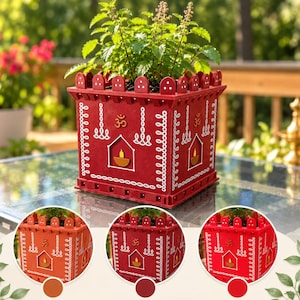 Puede incluir: Una maceta cuadrada roja con borde superior festoneado, con patrones pintados en blanco, un símbolo Om y un recorte central de una lámpara diya. La maceta contiene una planta verde y se muestra en tres variaciones de color: terracota, granate y rojo.