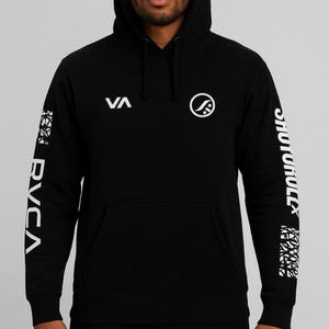 Pode incluir: Moletom preto com logotipos e texto brancos. A manga esquerda apresenta "RVCA" em branco, enquanto a manga direita exibe "SHOTOHULLX". A frente tem "VA" e um logotipo circular. Um moletom com capuz clássico.