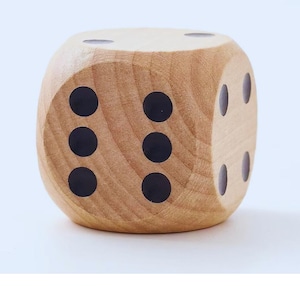May include: A large wooden die with black dots. The die is made of light-colored wood and has six sides, each with a different number of black dots. The die is a classic game piece.