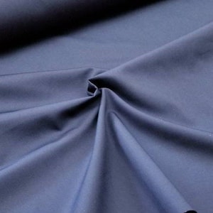 May include: A close-up of a smooth, dark blue fabric. The fabric is folded and draped, showing its texture and color.