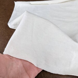 Puede incluir: Primer plano de una tela blanca, mostrando su textura y superficie lisa. La tela est&aacute; doblada y parece suave y ligera.