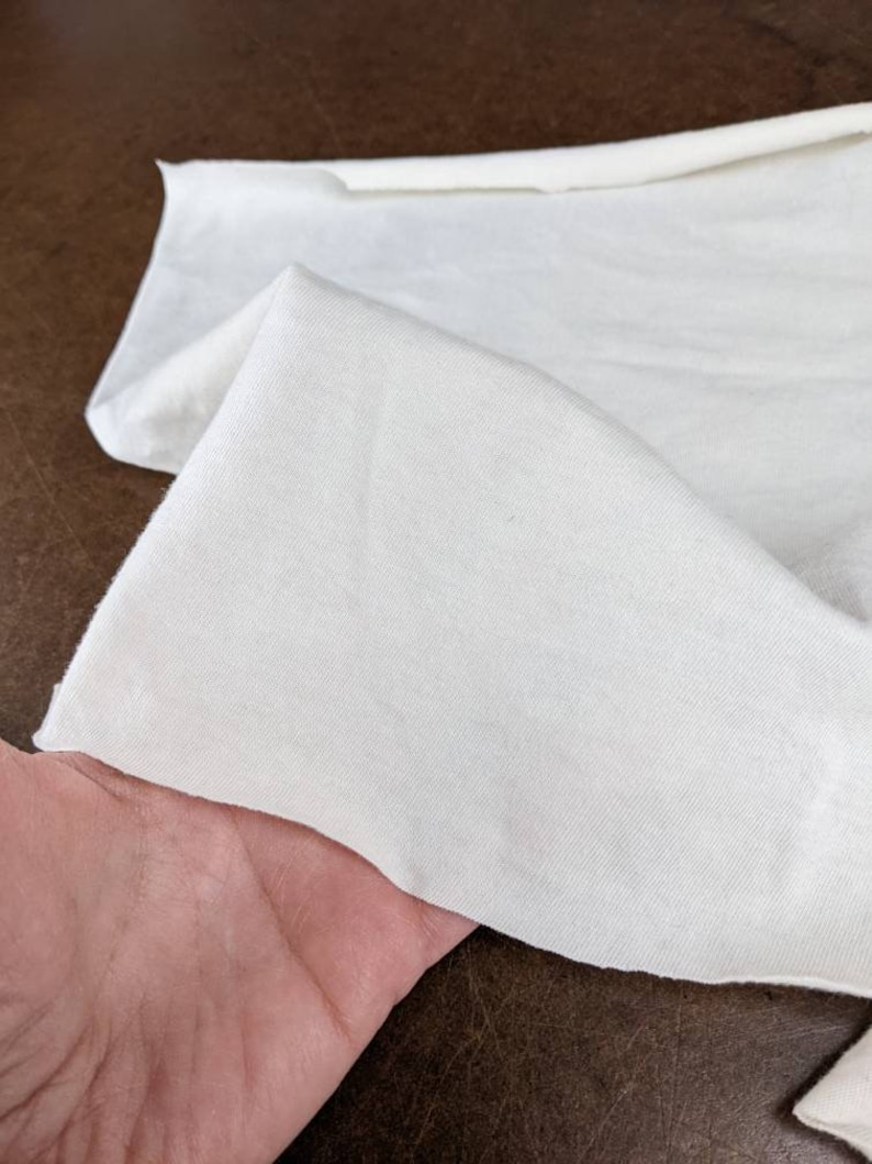 Puede incluir: Primer plano de una tela blanca, mostrando su textura y superficie lisa. La tela est&aacute; doblada y parece suave y ligera.