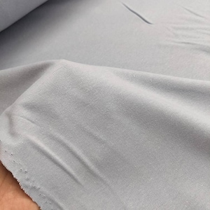 May include: A light blue fabric with a soft, textured surface. The fabric is folded and appears to be a knit material.