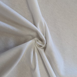 May include: White fabric with a smooth texture, folded and draped to show its soft, flowing quality.