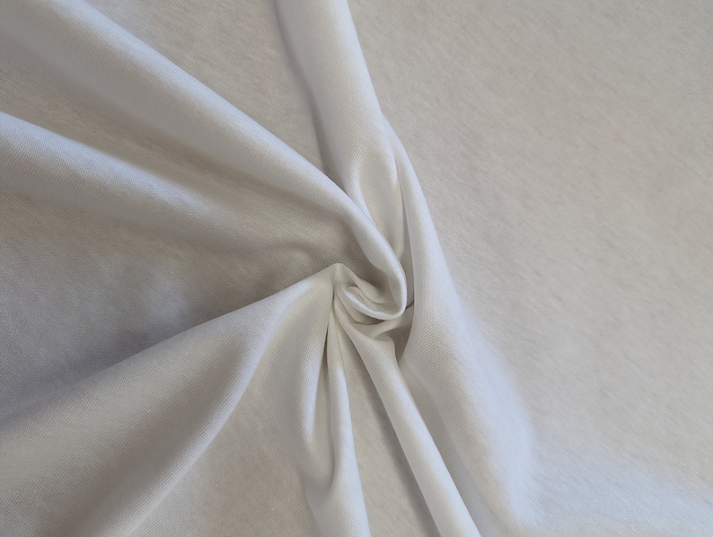 May include: White fabric with a smooth texture, folded and draped to show its soft, flowing quality.