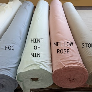 May include: Five rolls of fabric in different colors: light blue, light green, light pink, and beige. The fabric rolls are labeled "Fog", "Hint of Mint", "Mellow Rose", and "Stone".